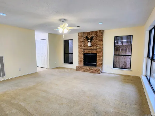 an empty room with windows and fireplace