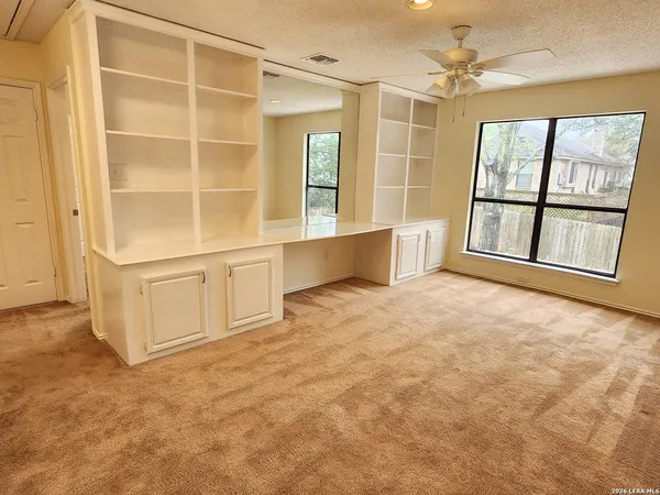 an empty room with windows and cabinet