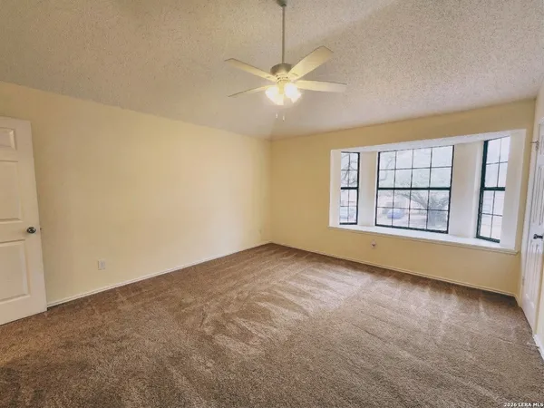 an empty room with windows and ceiling fan
