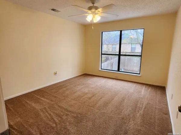 an empty room with windows and ceiling fan