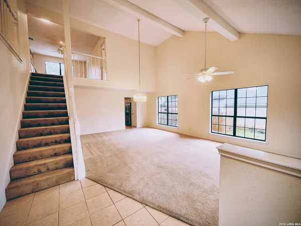 a view of an empty room with wooden floor and windows