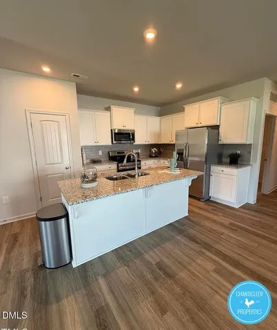 a kitchen with stainless steel appliances granite countertop a refrigerator a stove top oven a sink and cabinets