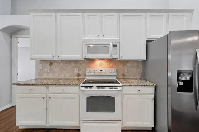 a kitchen with granite countertop white cabinets and refrigerator