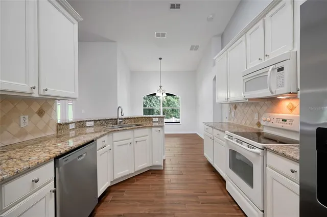 a kitchen with granite countertop white cabinets and white appliances