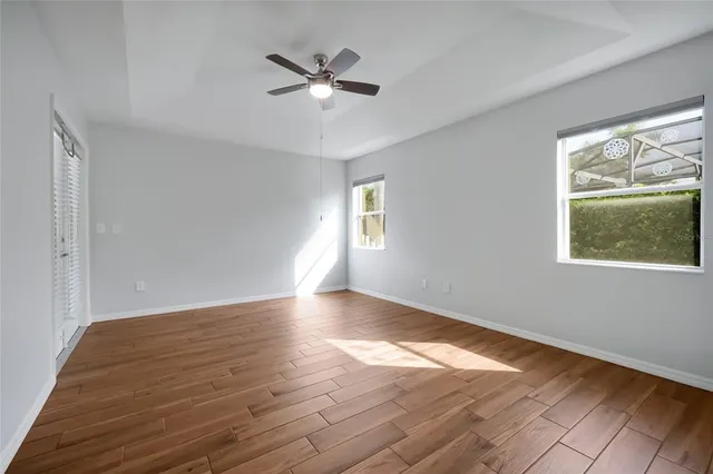 a view of an empty room with wooden floor and a window