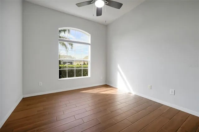 a view of an empty room with wooden floor fireplace and a window