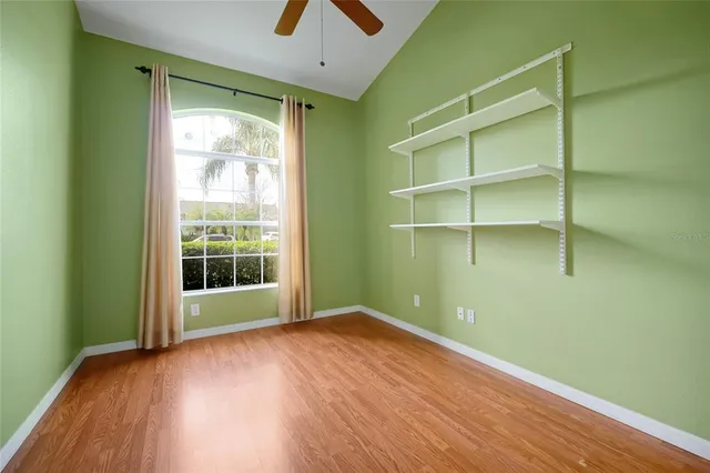 a view of empty room with wooden floor and fan