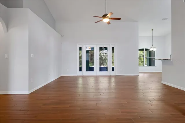 a view of an empty room with window and wooden floor