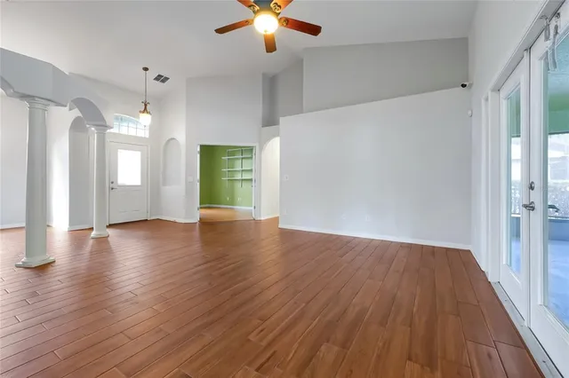 a view of an empty room with wooden floor and a window