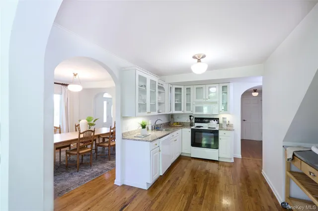 a kitchen with a stove and white cabinets with wooden floor