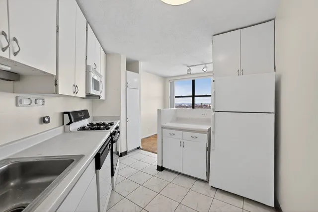 a kitchen with white cabinets and appliances