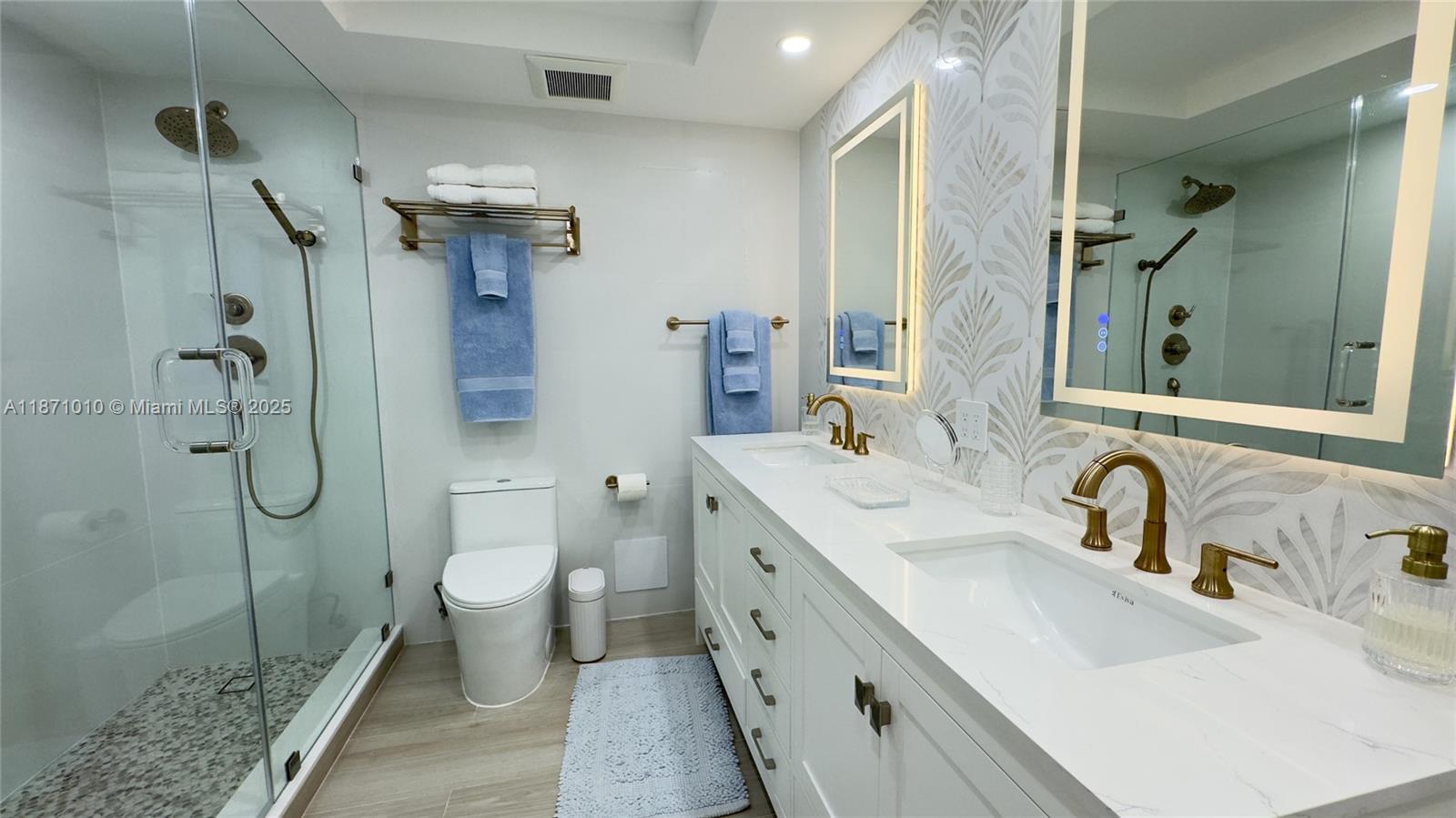 5161 Collins Avenue, Unit 715 Miami Beach, FL 33140 - Photo 12 of 31 a bathroom with a double vanity sink toilet mirror and shower