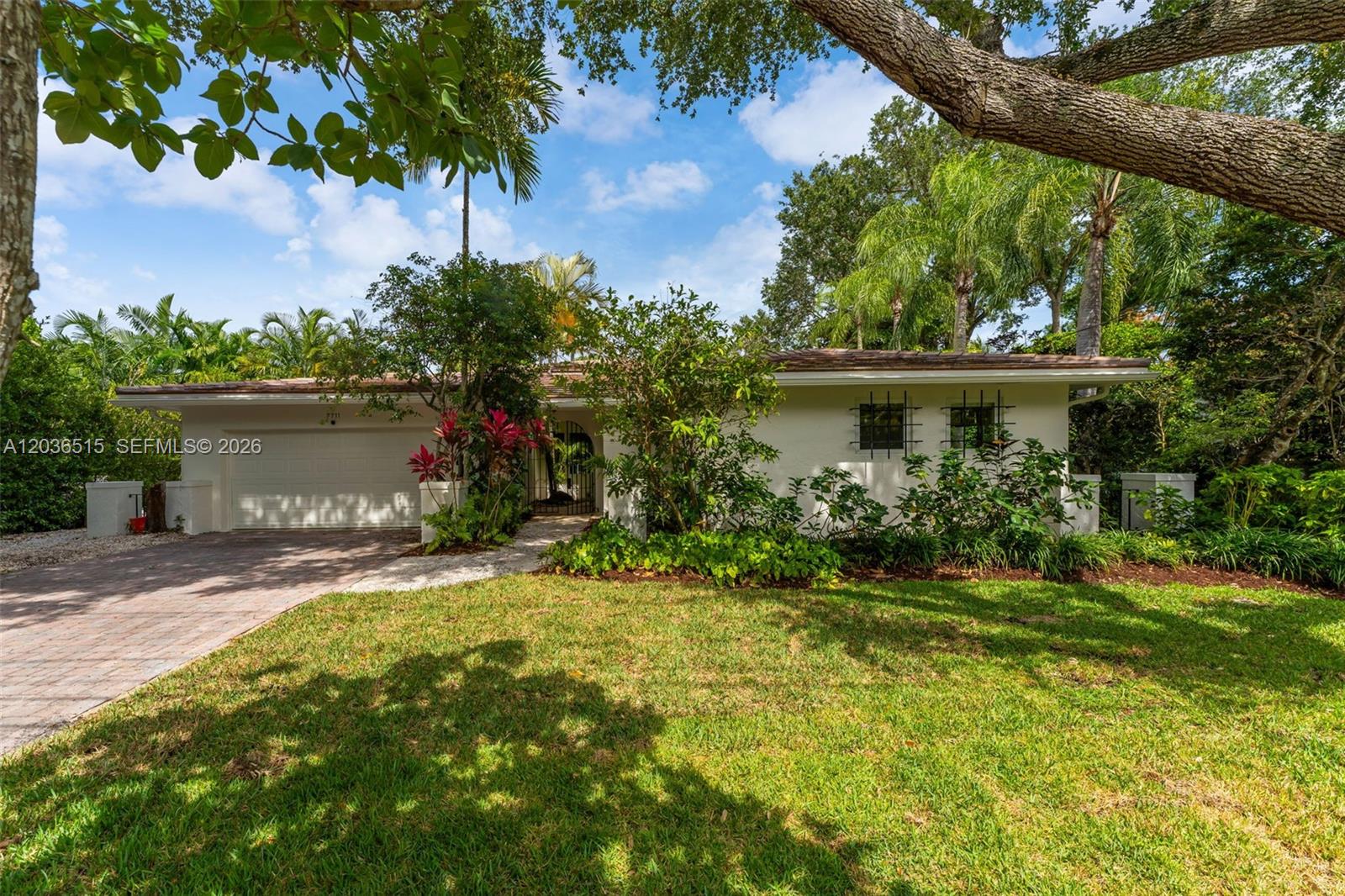 7711 Erwin Road Coral Gables, FL 33143 - Photo 2 of 26 a front view of a house with a yard and a garden