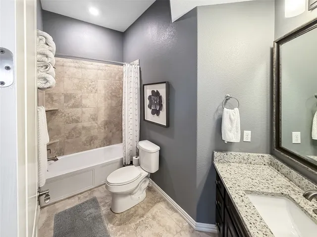 a bathroom with a granite countertop sink a toilet and shower