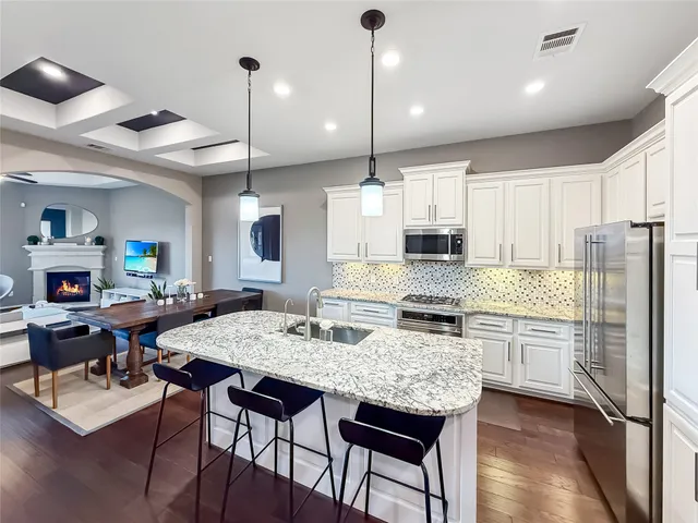 a kitchen with stainless steel appliances granite countertop a stove refrigerator a dining table and chairs with wooden floor