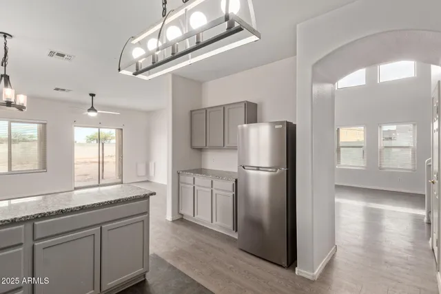 a kitchen with stainless steel appliances granite countertop a sink dishwasher a stove and a refrigerator with wooden floor