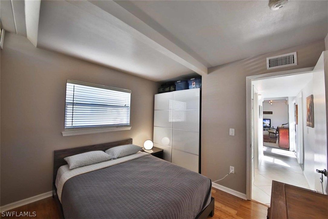 2979 Holly Road Fort Myers, FL 33901 - Photo 19 of 24 a bedroom with a bed and wooden floor