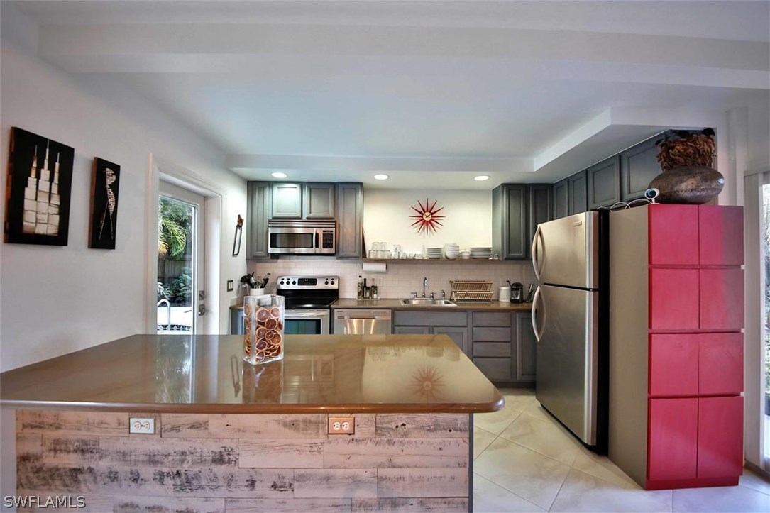 2979 Holly Road Fort Myers, FL 33901 - Photo 7 of 24 a kitchen with stainless steel appliances granite countertop a refrigerator a stove and a sink