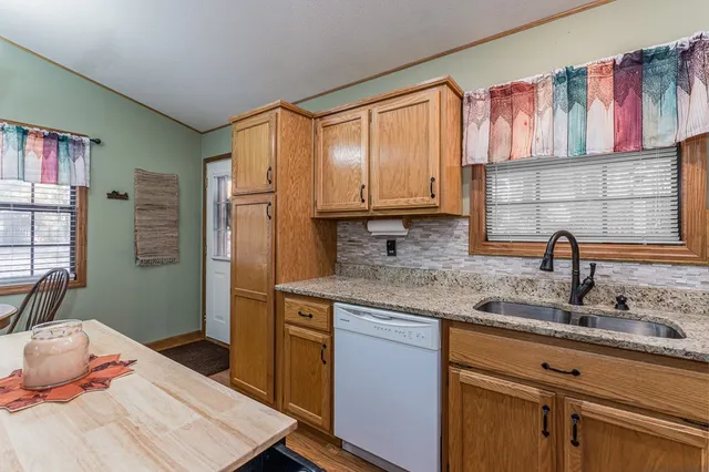 a kitchen with stainless steel appliances granite countertop a sink dishwasher stove and cabinets with wooden floor