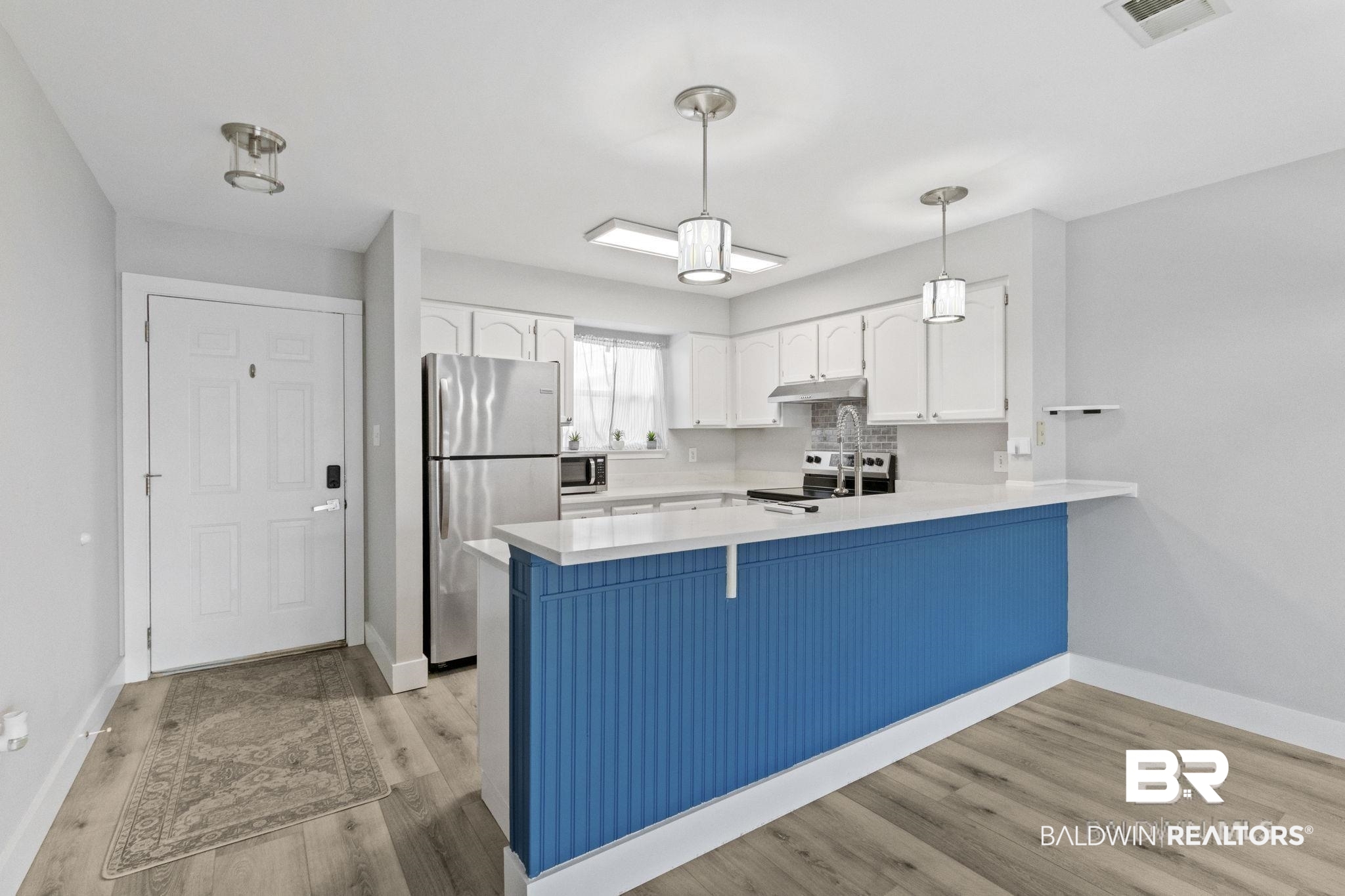 25861 Canal Road, Unit 77 Orange Beach, AL 36561 - Photo 14 of 48 Kitchen featuring white cabinets, decorative light fixtures, a peninsula, and appliances with stainless steel finishes