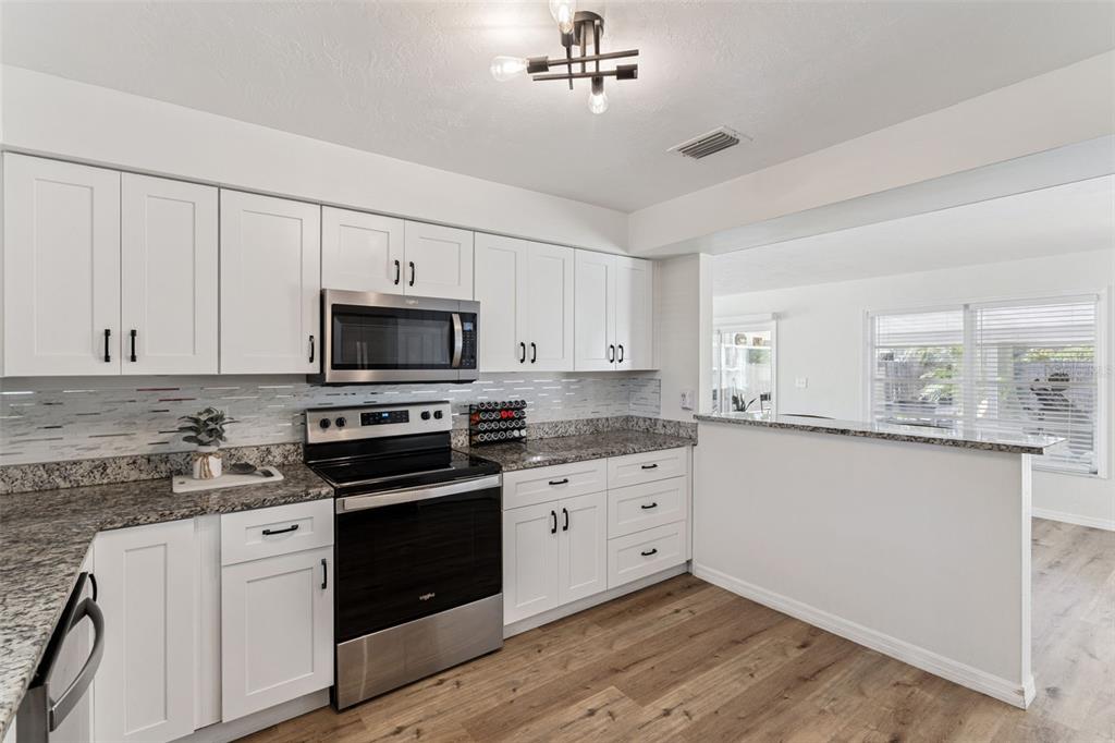 1051 Eva Street Deltona, FL 32725 - Photo 11 of 50 a kitchen with granite countertop white cabinets and stainless steel appliances