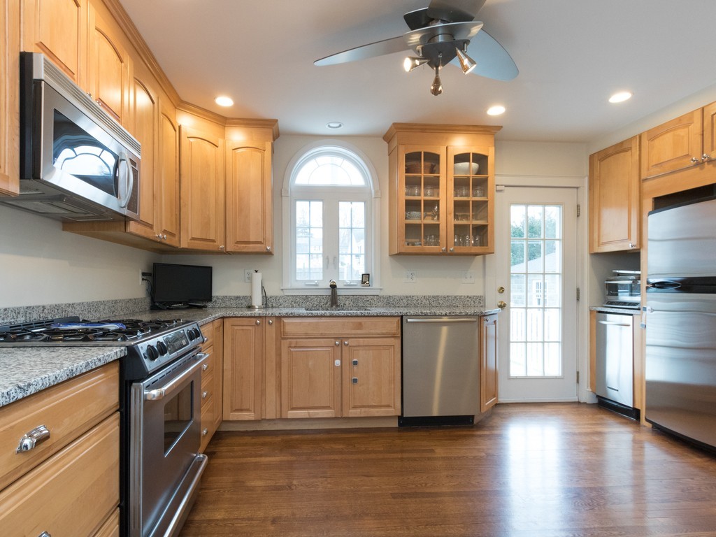 27 Churchill Road Boston, MA 02132 - Photo 4 of 30 a kitchen with stainless steel appliances granite countertop a stove top oven a sink dishwasher a refrigerator and a dining table with wooden floor