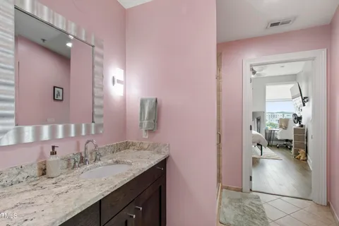 a en suite bathroom with a granite countertop sink and a mirror