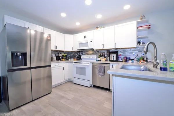 a kitchen with white cabinets and white appliances