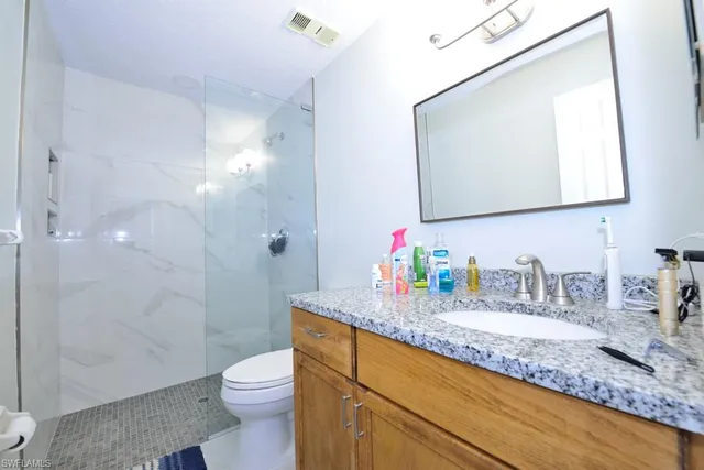 a bathroom with a granite countertop sink a toilet and a mirror