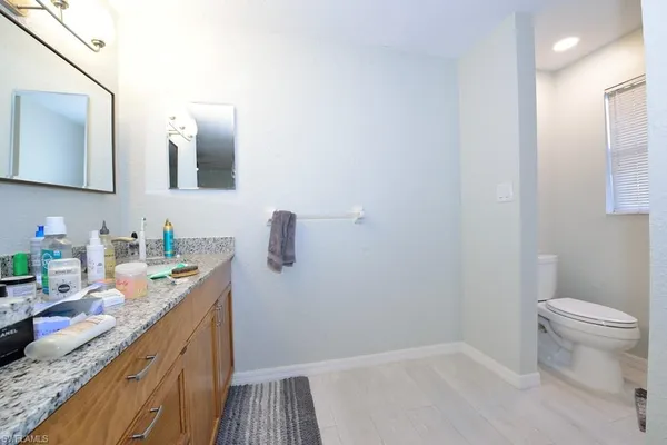 a bathroom with a granite countertop sink a toilet and mirror