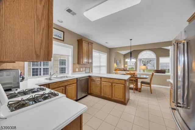 a large kitchen with stainless steel appliances a stove a sink dishwasher and white cabinets with wooden floor
