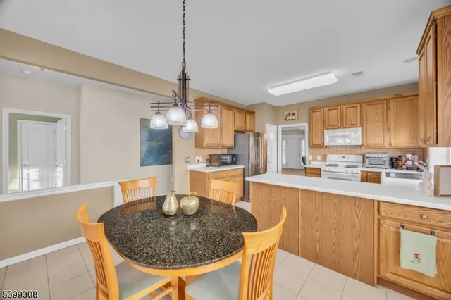 a kitchen with stainless steel appliances granite countertop a sink a stove a dining table and chairs