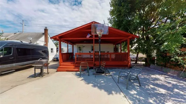 a view of a patio with table and chairs under an umbrella with a barbeque