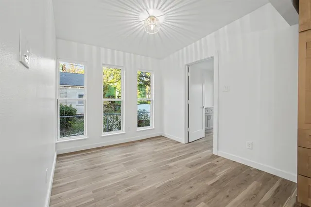 a view of an empty room with window and wooden floor