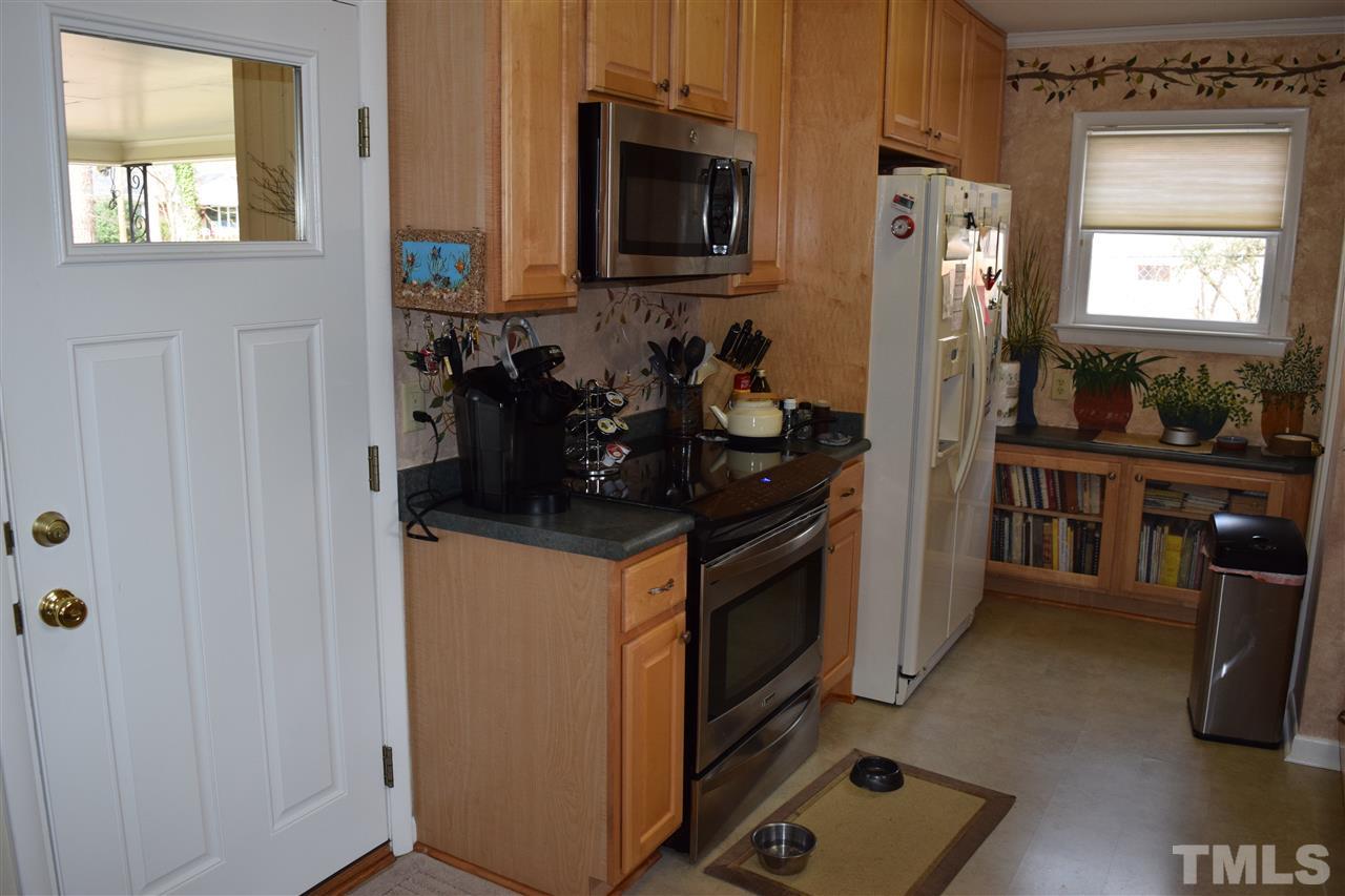 6908 Justice Drive Raleigh, NC 27615 - Photo 11 of 15 Another view of kitchen showing induction range, refrigerator, microwave, and door to carport