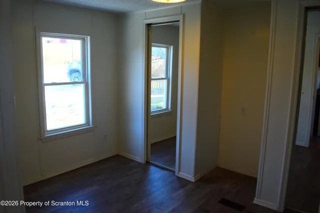 a view of an empty room with wooden floor and closet