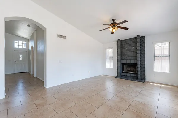 an empty room with chandelier fan and windows