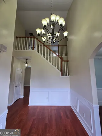 a view of a room with wooden floor chandelier and a window