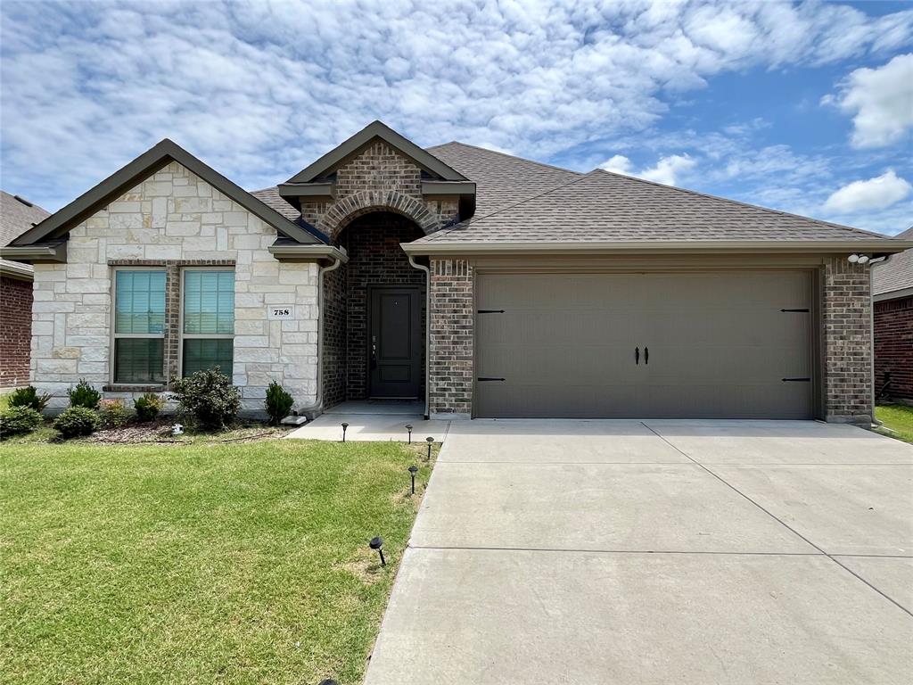 758 Musket Street Fate, TX 75189 - Photo 2 of 26 French country style house with an attached garage, driveway, a front lawn, a shingled roof, and stone siding