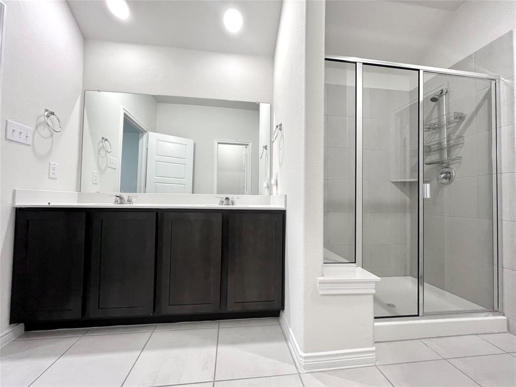 758 Musket Street Fate, TX 75189 - Photo 21 of 26 Full bath featuring double vanity, a shower stall, and tile patterned flooring