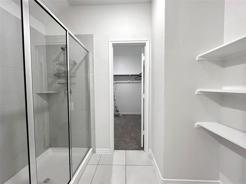 758 Musket Street Fate, TX 75189 - Photo 23 of 26 Bathroom featuring a stall shower, a spacious closet, and tile patterned floors