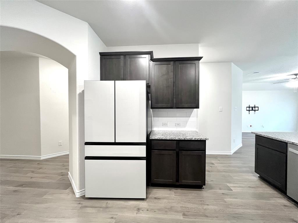 758 Musket Street Fate, TX 75189 - Photo 7 of 26 Kitchen featuring freestanding refrigerator, light wood-style floors, arched walkways, dishwashing machine, and dark brown cabinets