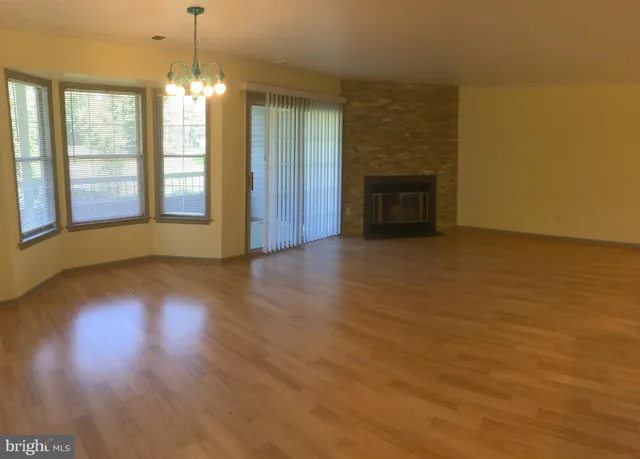 an empty room with wooden floor fireplace and windows