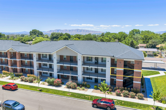 572 South 100 West, Unit E210 Springville, UT 84663 - Photo 4 of 35 Multi-story residential building featuring brick and white siding, individual balconies, and a dark shingle roof