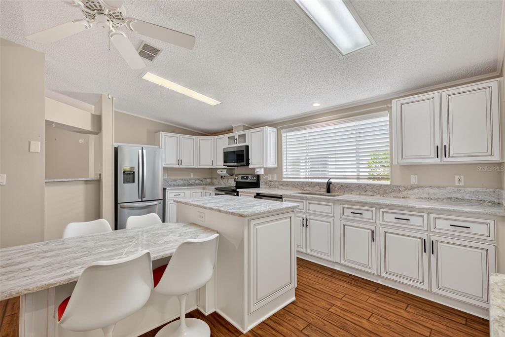 3024 Manatee Road Tavares, FL 32778 - Photo 13 of 39 a kitchen with stainless steel appliances granite countertop a sink a stove a refrigerator cabinets and chairs