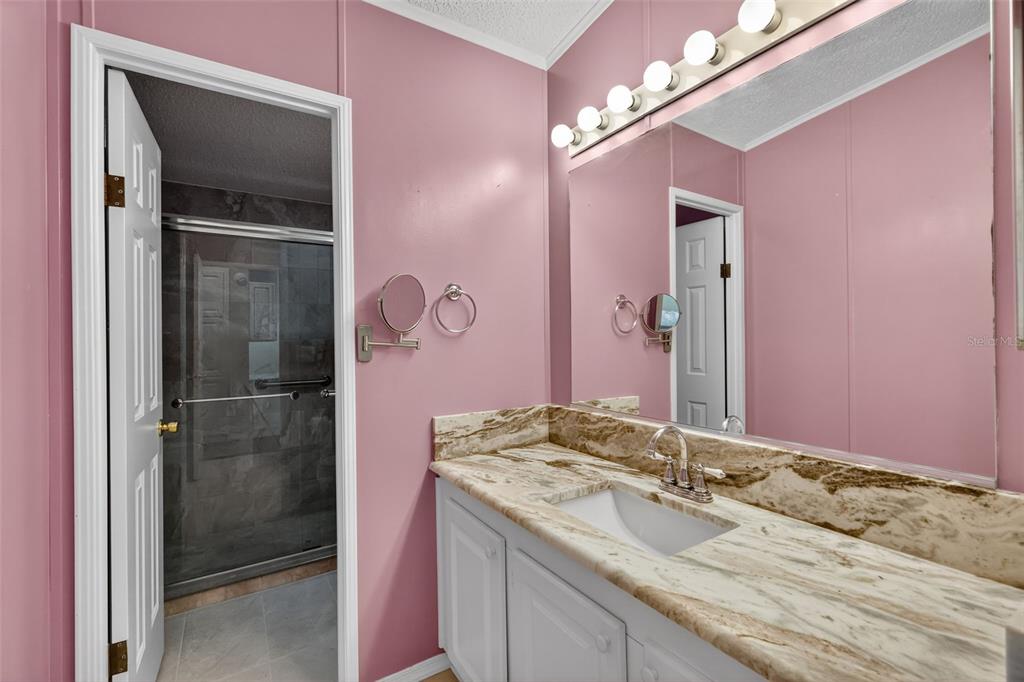 3024 Manatee Road Tavares, FL 32778 - Photo 23 of 39 a bathroom with a granite countertop sink a mirror and a shower