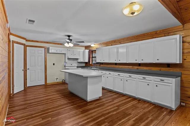 a kitchen with stainless steel appliances granite countertop a sink cabinets and wooden floor