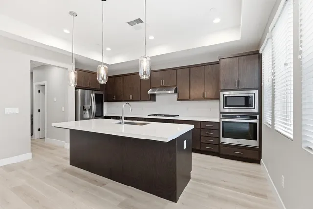 a kitchen with stainless steel appliances granite countertop a sink a stove and a refrigerator