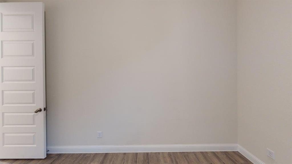 3314 Willena Road Melissa, TX 75454 - Photo 13 of 24 Light-toned walls with wood-finish flooring, featuring a paneled interior door with a dark-finished knob