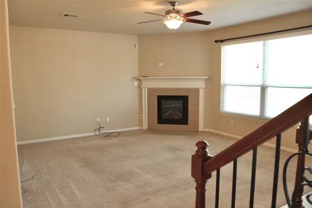 a view of an empty room with chandelier fan and fire place